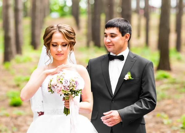 Novia y novio en un parque. Ramo de flores de boda nupcial — Foto de Stock