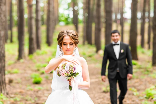 O noivo e a noiva num parque. Buquê de casamento nupcial de flores — Fotografia de Stock