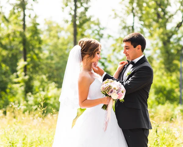 Vőlegény és a menyasszony a parkban. Esküvő menyasszonyi csokor virág — Stock Fotó