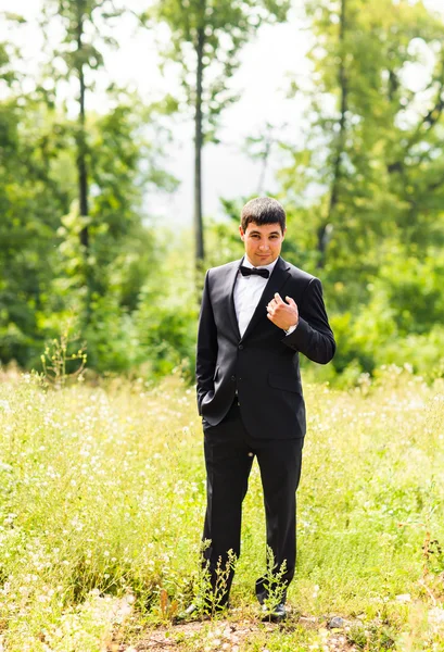 Close up portrait of handsome stylish groom in black classic suit outdoors Stock Picture