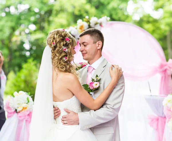 Feliz pareja romántica recién casada bailando en el pasillo de la boda con decoraciones de color rosa y flores — Foto de Stock