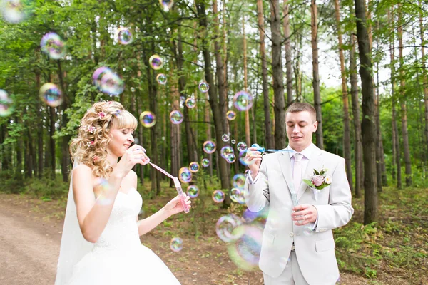 Beautiful wedding couple blowing bubbles — Stock Photo, Image