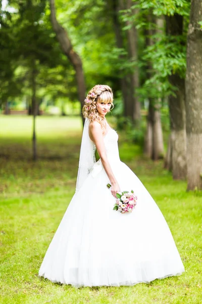 Hermosa novia con ramo de flores al aire libre en el parque verde . — Foto de Stock