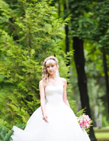 Mooie bruid met bruiloft boeket van bloemen buitenshuis in groen park. — Stockfoto