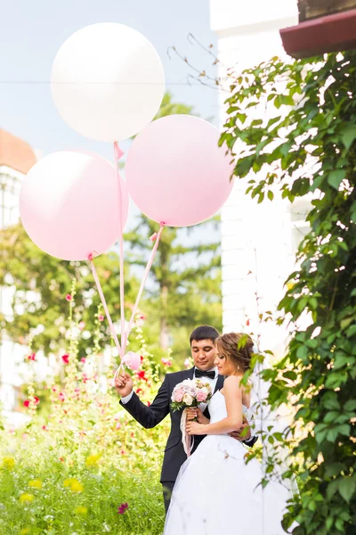 Zomervakantie, feest en bruiloft concept - echtpaar met kleurrijke ballonnen — Stockfoto