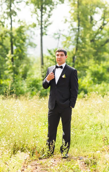 Retrato de belo noivo elegante em preto terno clássico ao ar livre — Fotografia de Stock