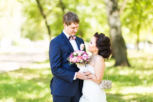 Bruidspaar knuffelen, het houden van een boeket bloemen, bruid bruidegom omarmen haar — Stockfoto