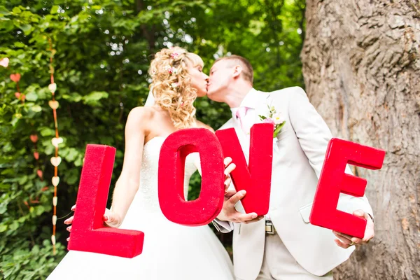 Bride and groom holding the letter word love — Stock Photo, Image