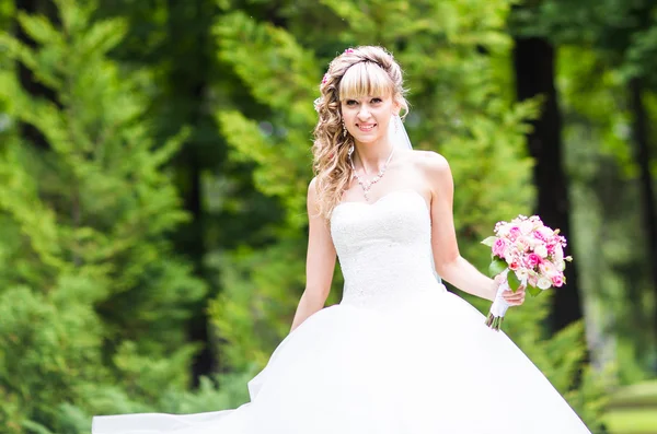 Bela noiva com buquê de casamento de flores ao ar livre no parque verde . — Fotografia de Stock