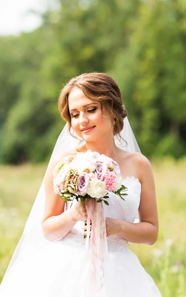 Bella sposa ragazza in abito da sposa e mazzo di fiori, ritratto all'aperto — Foto Stock