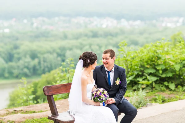 Atraktivní nevěsta a ženich seděl na lavičce — Stock fotografie