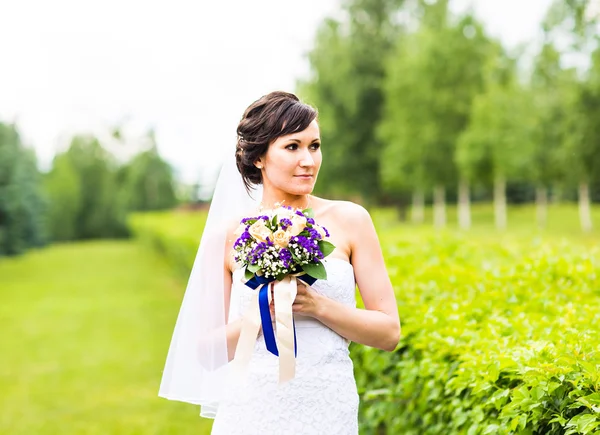 Dziewczyny piękne panny młodej w sukni ślubnej z bukietem kwiatów, portret na zewnątrz — Zdjęcie stockowe