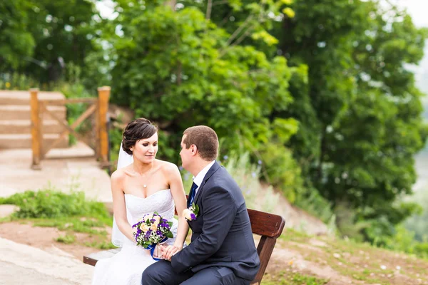 Attraktive Braut und Bräutigam auf einer Bank — Stockfoto