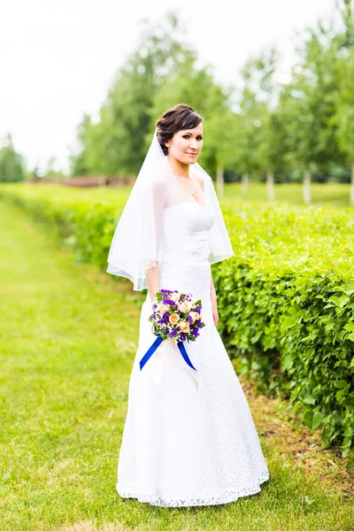 Menina noiva bonita em vestido de noiva com buquê de flores, ao ar livre retrato — Fotografia de Stock