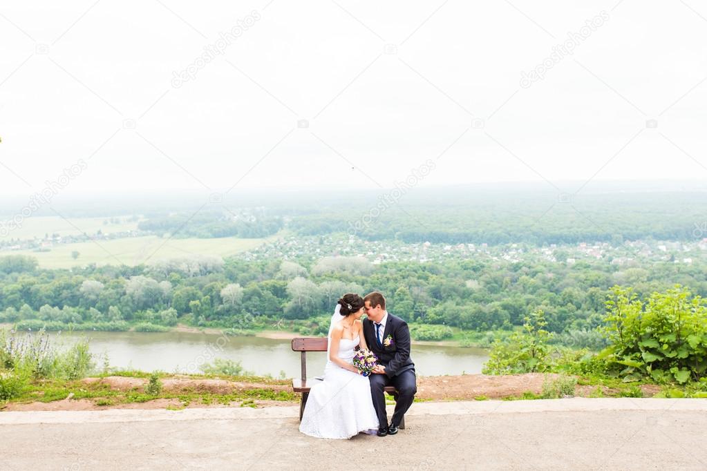 attractive bride and groom  sitting on a bench