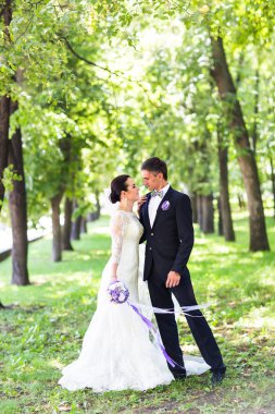 Şık gelin ve damat düğün günü dışarıda birlikte poz veriyorlar.