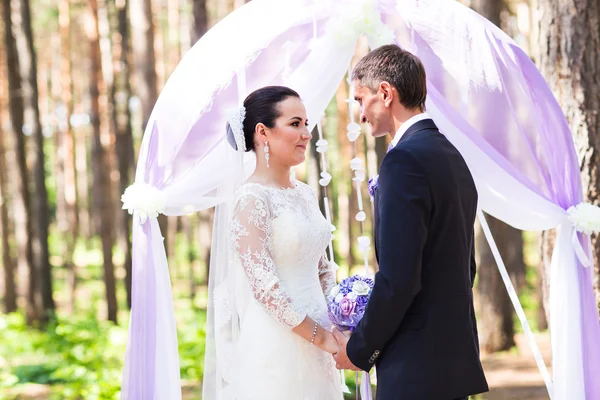 Braut und Bräutigam unter Hochzeitsbogen — Stockfoto