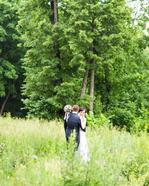 onu kucaklayan Düğün çifti, sarılma bir buket çiçek, holding gelin damat