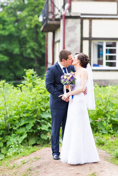 Casamento casal abraçando, a noiva segurando um buquê de flores, noivo abraçando-a — Fotografia de Stock