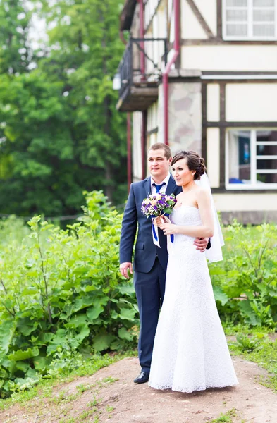 Bruidspaar knuffelen, het houden van een boeket bloemen, bruid bruidegom omarmen haar — Stockfoto