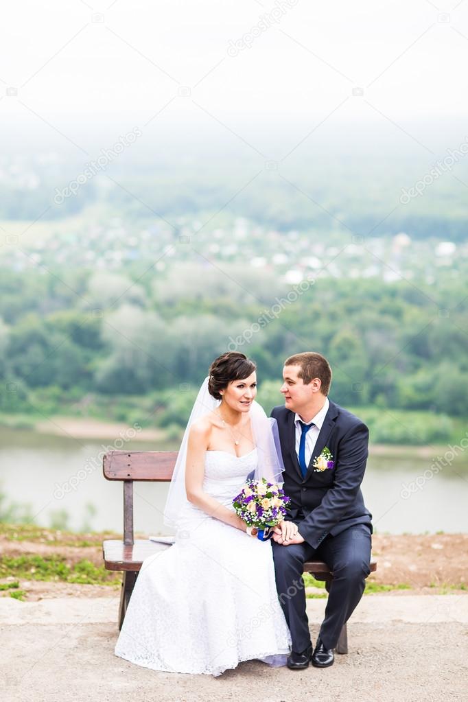 attractive bride and groom  sitting on a bench