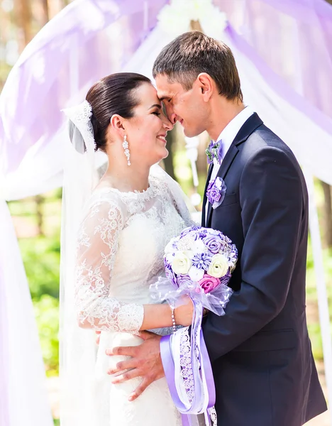 Bruid en bruidegom onder huwelijksboog — Stockfoto