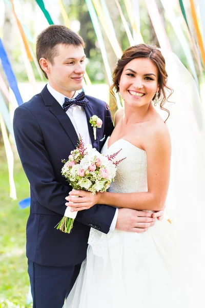 Matrimonio coppia baci, sposa in possesso di un mazzo di fiori, sposo abbracciarla — Foto Stock