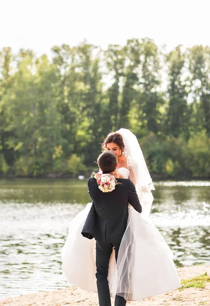 Ślub pary stojącej i całując w pobliżu jeziora. — Zdjęcie stockowe