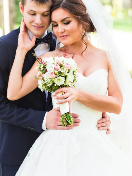 Sarılma, elinde bir buket çiçek, onu kucaklayan damat gelin düğün çifti — Stok fotoğraf
