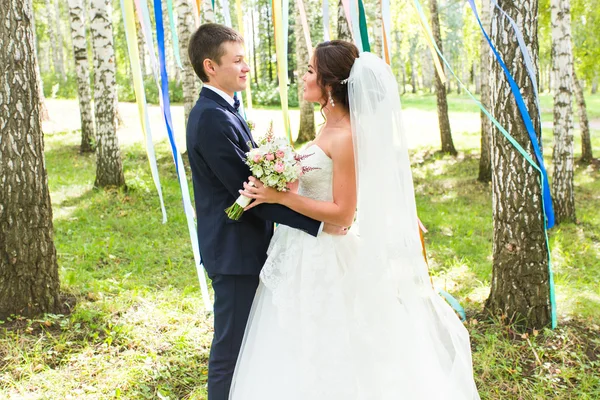 Matrimonio coppia abbracciare, sposa in possesso di un mazzo di fiori, sposo abbracciarla — Foto Stock