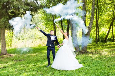 Evlilik, aşk, ilişki, evlilik. Gelin ve damat mavi duman ile gülümseyen