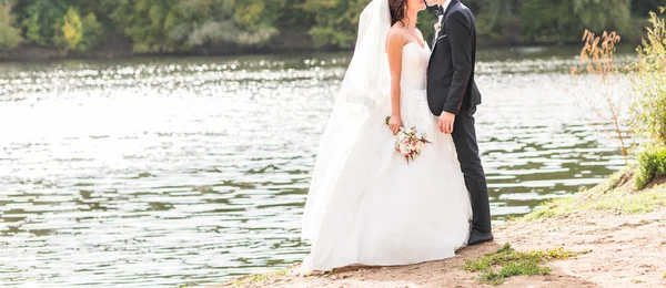 Hochzeitspaar steht und umarmt sich am See. — Stockfoto