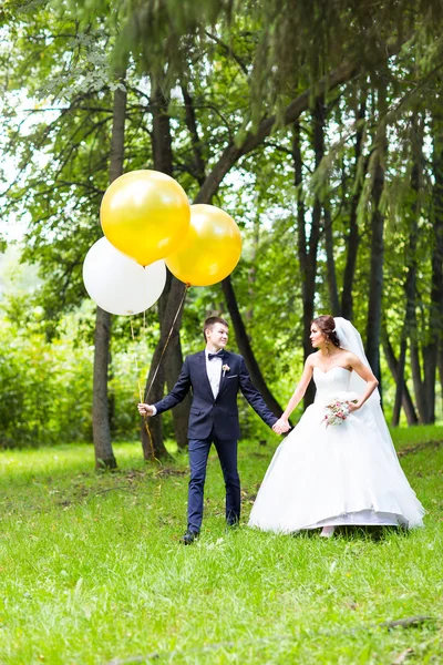 Bräutigam und Braut mit Luftballons im Freien — Stockfoto