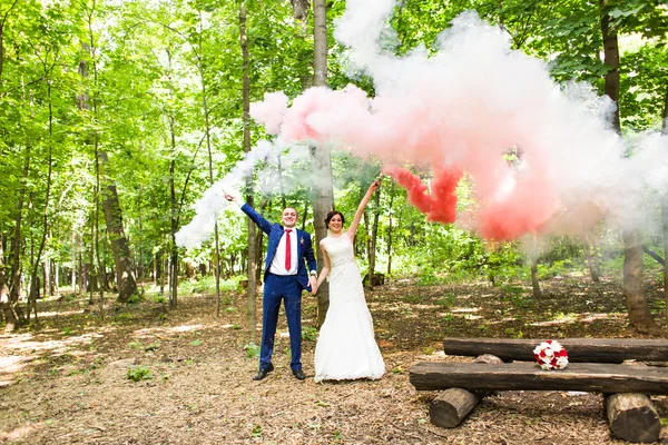 Ślub, miłość, związki, małżeństwo. Uśmiechnięty nowożeńcy i kolorowy dym — Zdjęcie stockowe