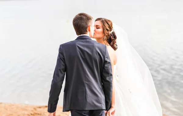Hochzeitspaar küsst sich am See. — Stockfoto
