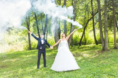 Evlilik, aşk, ilişki, evlilik. Gelin ve damat mavi duman ile gülümseyen