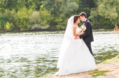 Düğün çift ayakta ve göl kenarında sarılma.