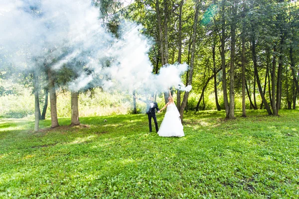 Mariage, amour, relations, mariage. Mariée souriante et marié avec de la fumée bleue — Photo