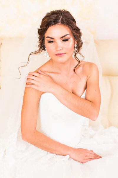 Красивая невеста в интерьере сидит на диване — стоковое фото