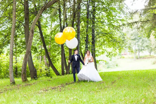 Bräutigam und Braut mit Luftballons im Freien — Stockfoto