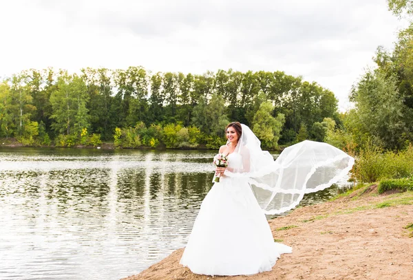 Panna młoda w białej sukni z Bukiet ślubny nad jeziorem — Zdjęcie stockowe