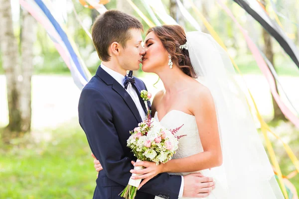 Hochzeitspaar umarmt, Braut hält Blumenstrauß in der Hand, der Bräutigam umarmt sie — Stockfoto