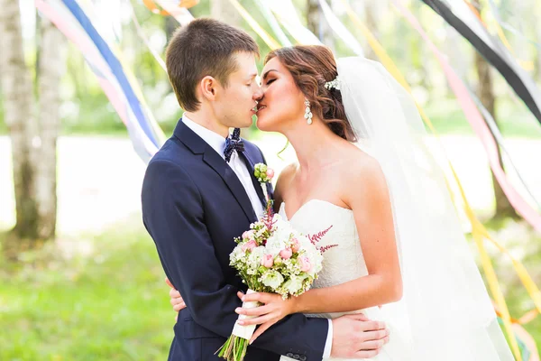 Casamento casal abraçando, noiva segurando um buquê de flores, o noivo abraçando-a — Fotografia de Stock