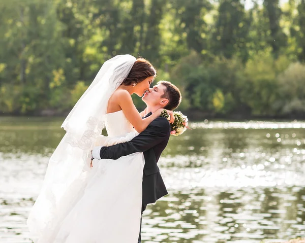 Matrimonio coppia in piedi e baciare vicino lago . — Foto Stock