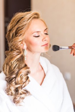 Düğün makyaj sanatçısı bir gelin için uyduruyor. Güzel seksi model kız kapalı. Güzellik sarışın kadın kıvırcık saçlı. Yakın çekim yakışıklı yüz yakınındaki