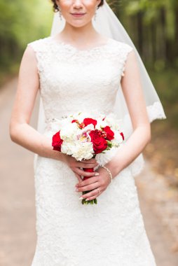 Güzel gelin bir parkta açık havada düğün buketi ile.