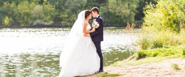 Düğün çift ayakta ve göl kenarında sarılma.