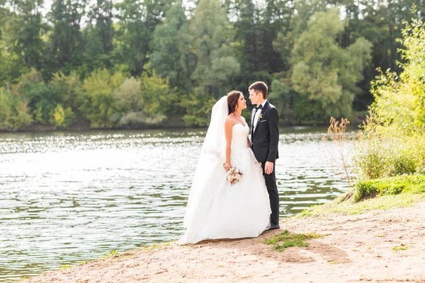 Couple de mariage debout et câlin près du lac . — Photo