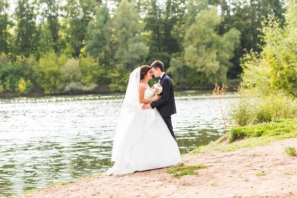 Couple de mariage debout et câlin près du lac . — Photo