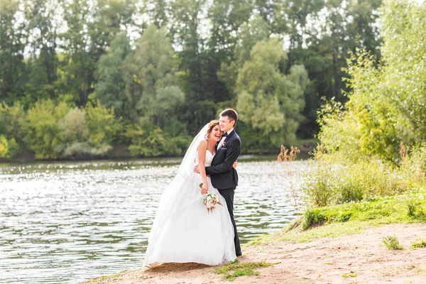 Bruiloft paar staande en knuffelen in de buurt van lake. — Stockfoto